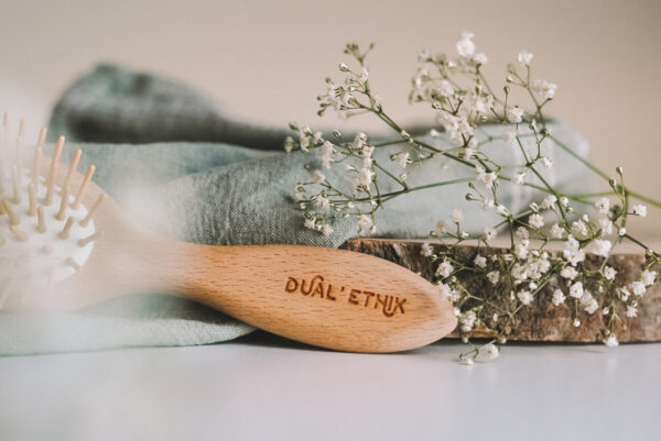 Brosse à cheveux avec Dual'Ethik écrit sur le manche